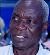 Retrato em grande plano de Vicy António, antiga glória do futebol angolano. É um homem negro de idade avançada, com cabelo curto grisalho e expressão serena mas resiliente. Ele veste uma camisa clara e olha ligeiramente para o lado com um meio sorriso.